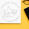 Custom Library Embossing Stamp - Personalized Book Name Embosser with Soft Swift Shark Design - 'This Book Belongs to' Paper Embosser - Available in Red, Blue, Grey, or Pink Handle - 1-5/8 Size view 1